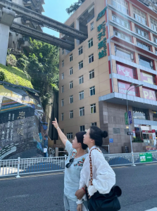 重慶李子壩輕軌穿樓景點,兩位遊客抬頭觀看輕軌打卡留念