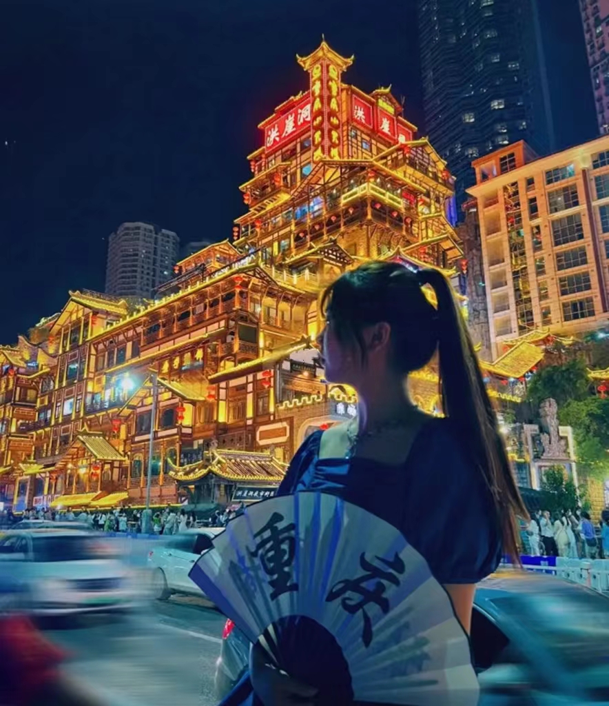 重慶洪崖洞夜景，女生持扇與山城吊腳樓燈光合照打卡